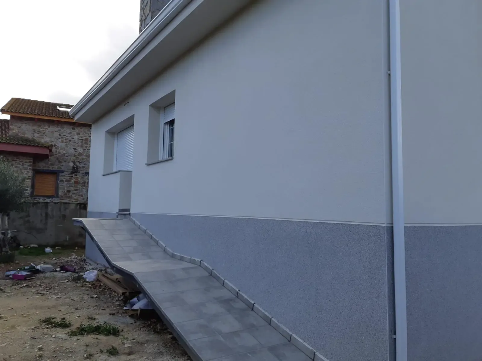Encuentro entre el cuerpo blanco y el zócalo gris en el lateral de la vivienda