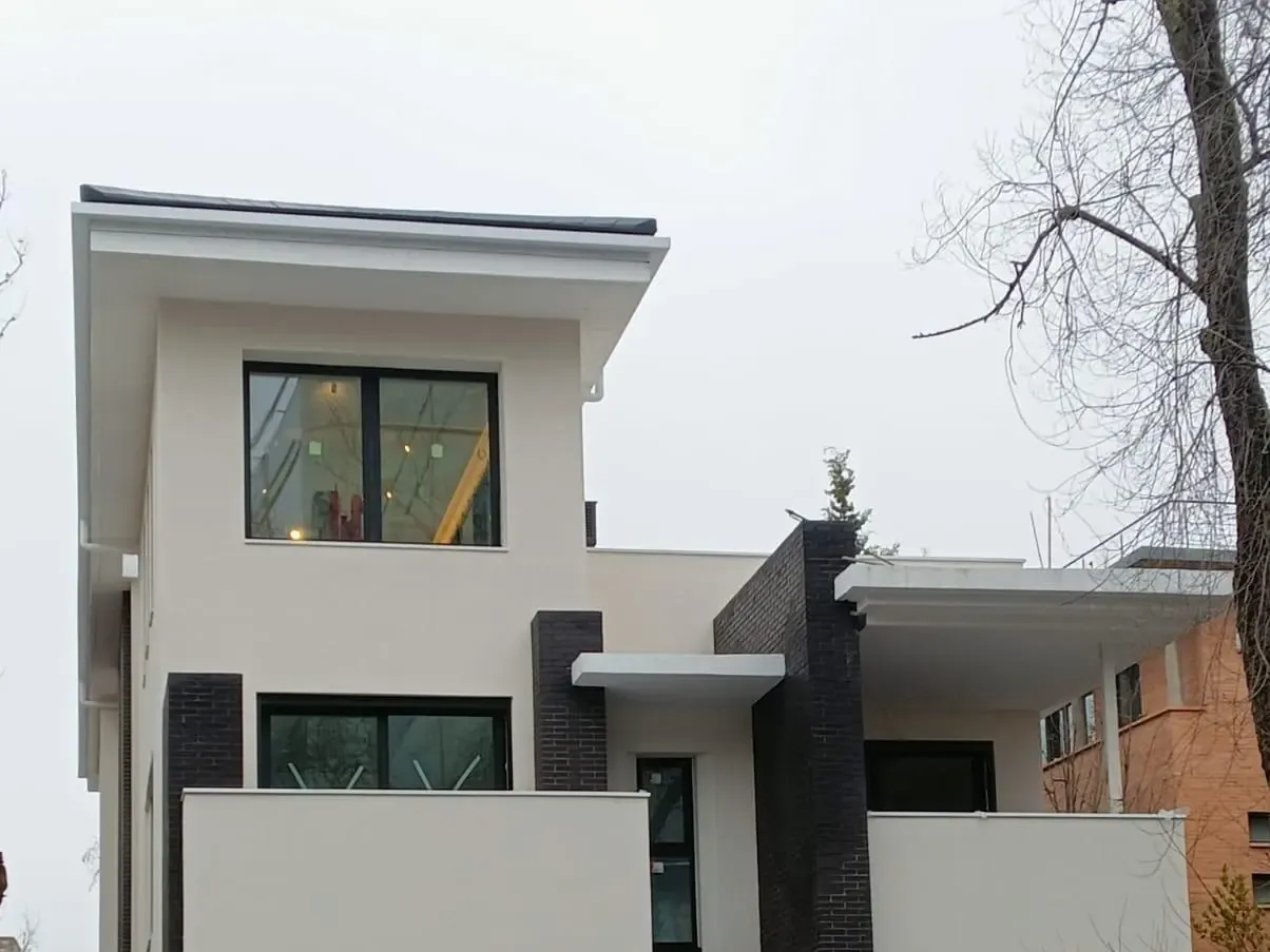 Fachada principal con el SATE terminado en blanco junto a los cuerpos oscuros